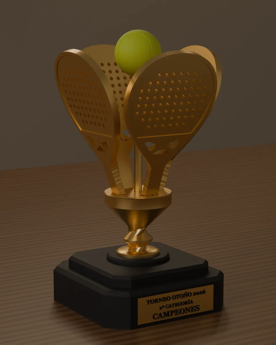 Copa dorada de cuatro palas con una pelota, con placa del torneo, sobre una mesa de madera